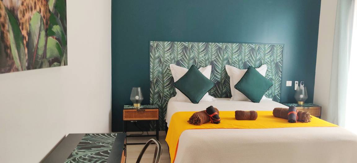 Chambre double aux tons vert émeraude avec tête de lit tropicale