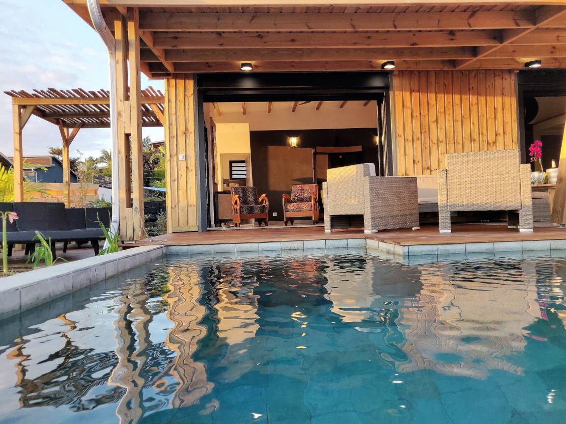 Piscine et salon extérieur sous la varangue en bois de la villa