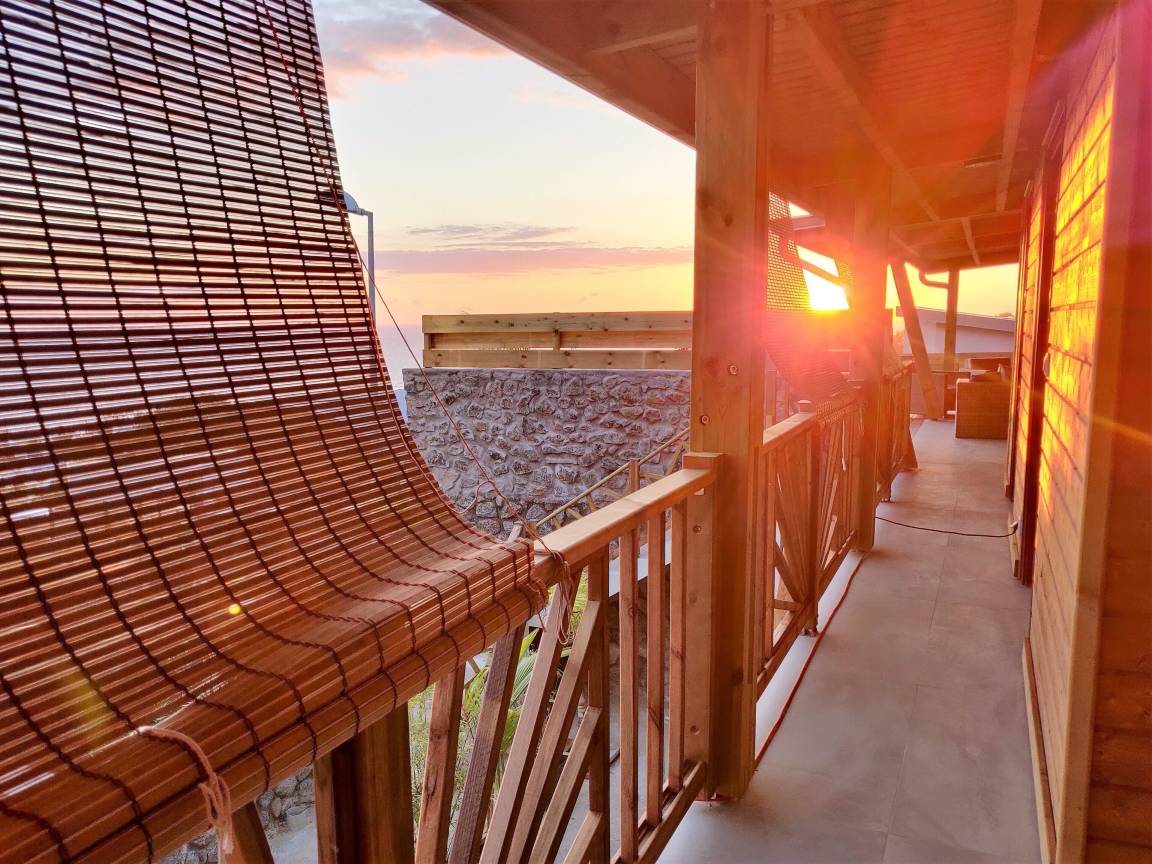 Coursive en bois de la villa baignée par la lumière du coucher de soleil