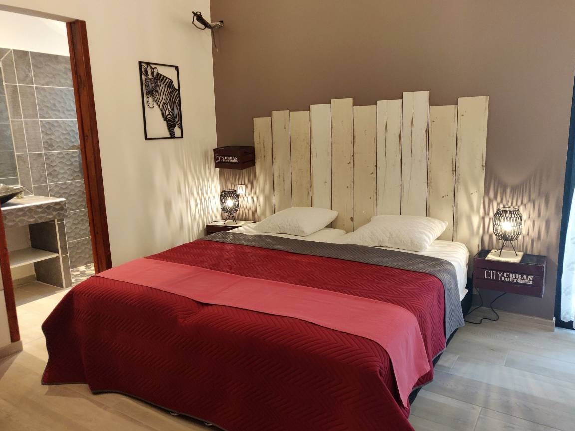 Chambre king size avec tête de lit en bois blanchi et salle de bain privative