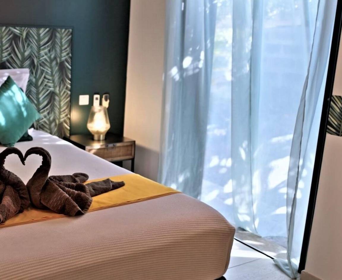 Chambre lumineuse avec voilages, linge soigné et tête de lit feuillage