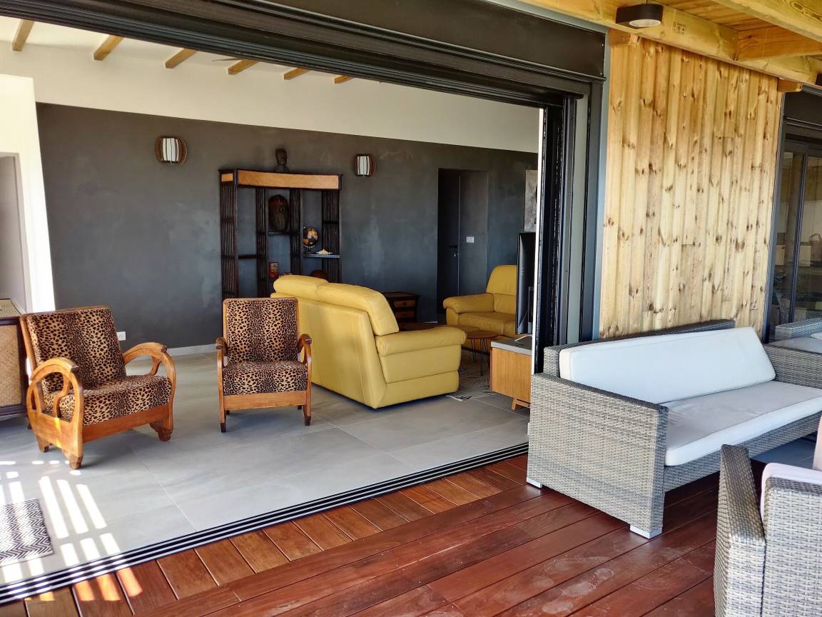 Séjour ouvert sur le deck avec fauteuils léopard et canapés en cuir jaune