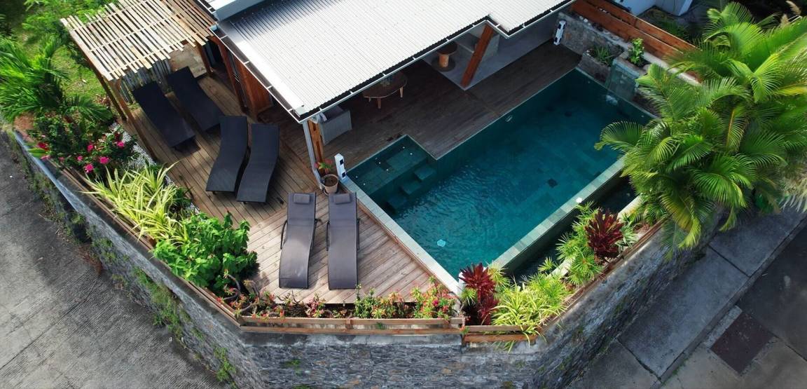 Vue aérienne de la villa, du deck en bois, des transats et de la piscine