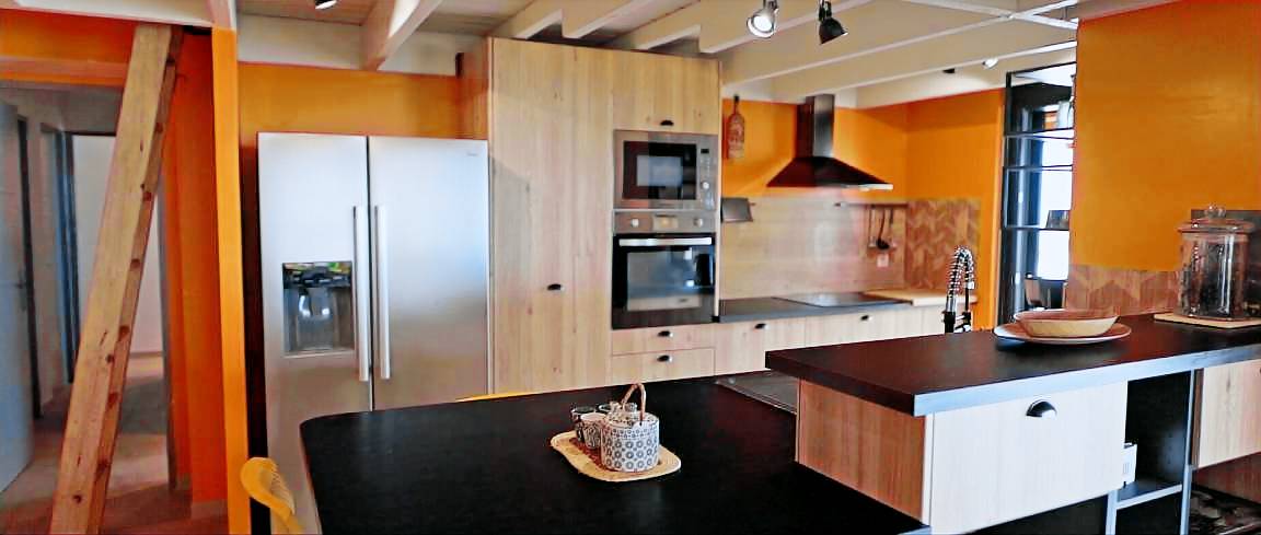 Îlot central de la cuisine avec four, plaques induction et grand réfrigérateur