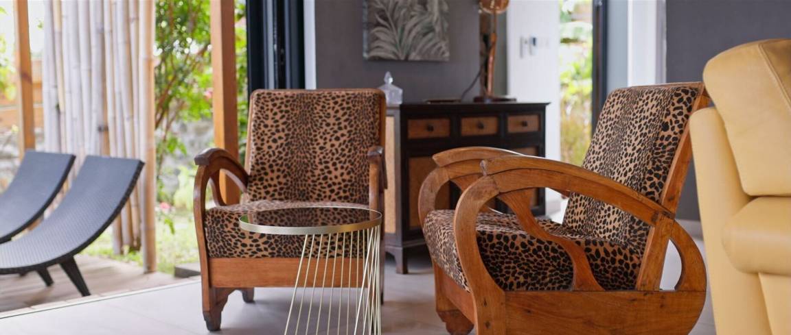Fauteuils coloniaux en bois tapissés léopard ouverts sur le jardin